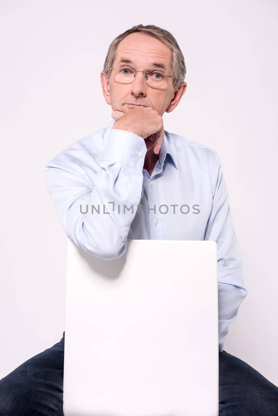 Pensive senior man sitting behind ad board