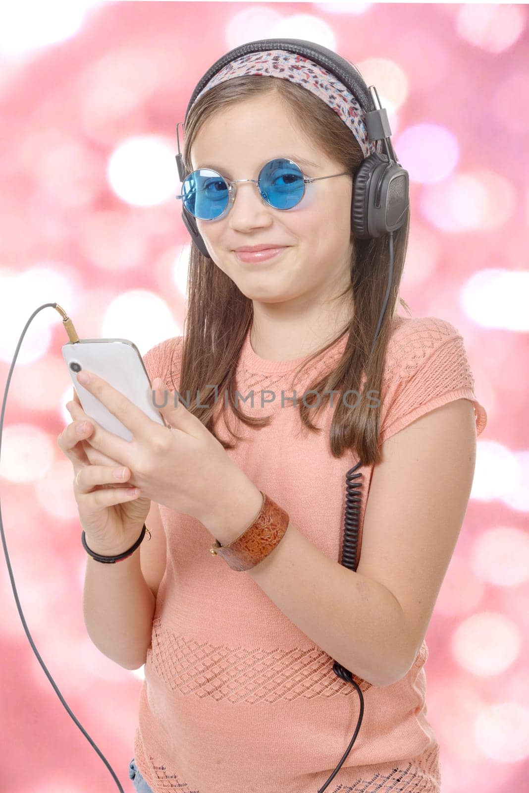 A preteen girl listening to music with his smartphone, bokeh background