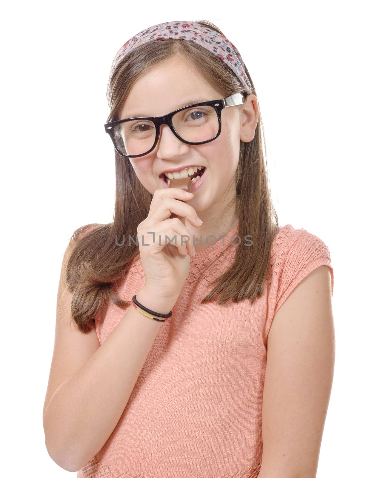 a preteen  girl eats chocolate, isolated on white