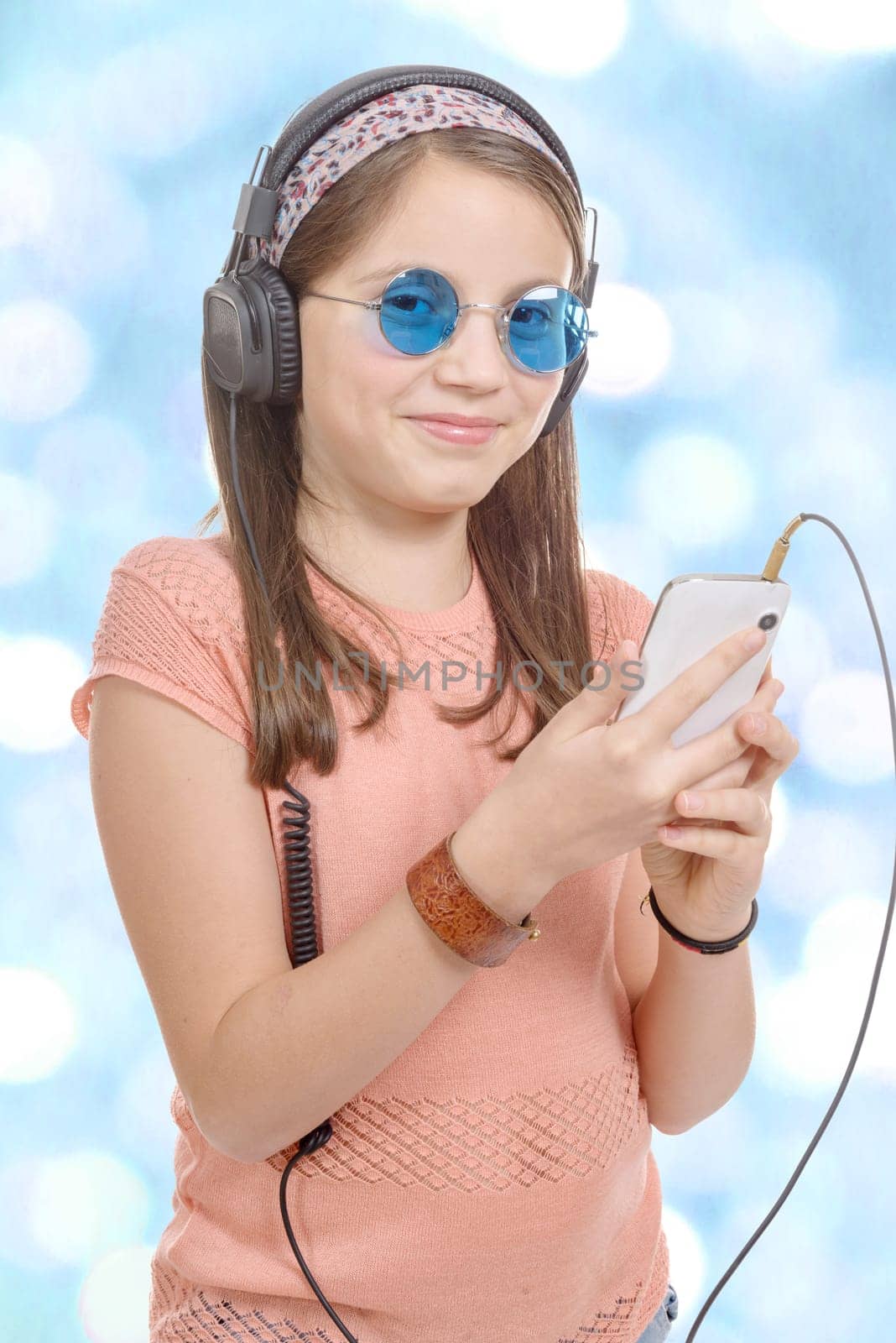 A preteen girl listening to music with his smartphone, bokeh background