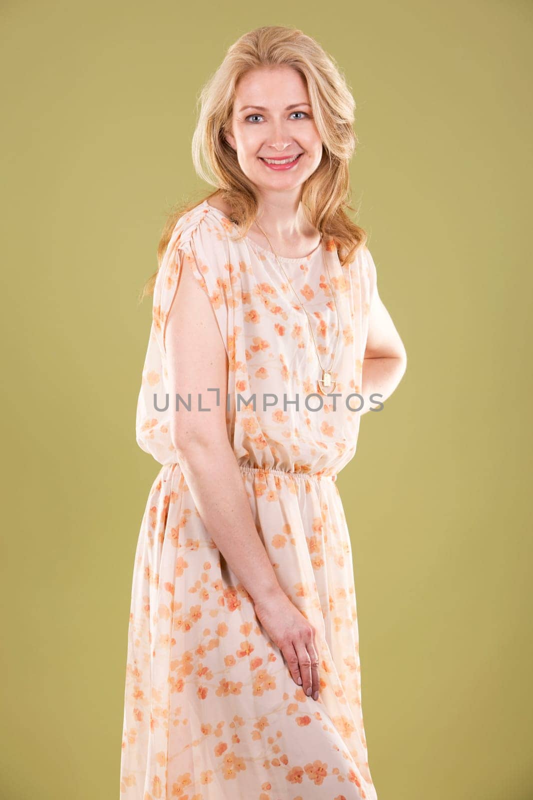 blond woman wearing beige dress on green background