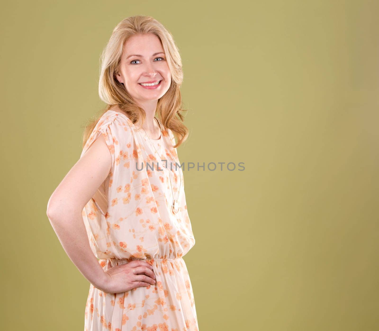 blond woman wearing beige dress on green background
