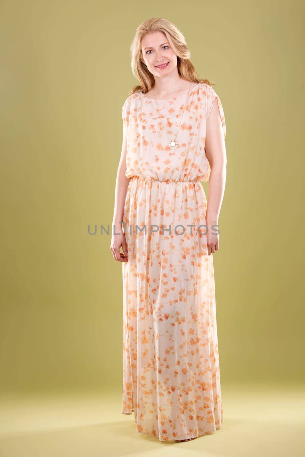 blond woman wearing beige dress on green background
