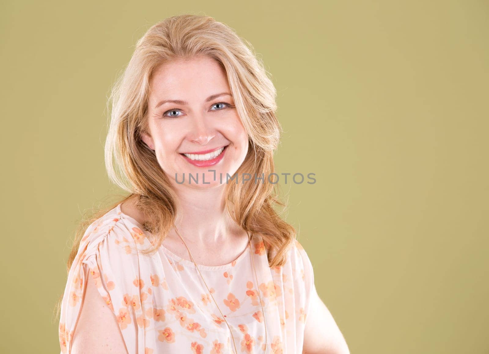 blond woman wearing beige dress on green background