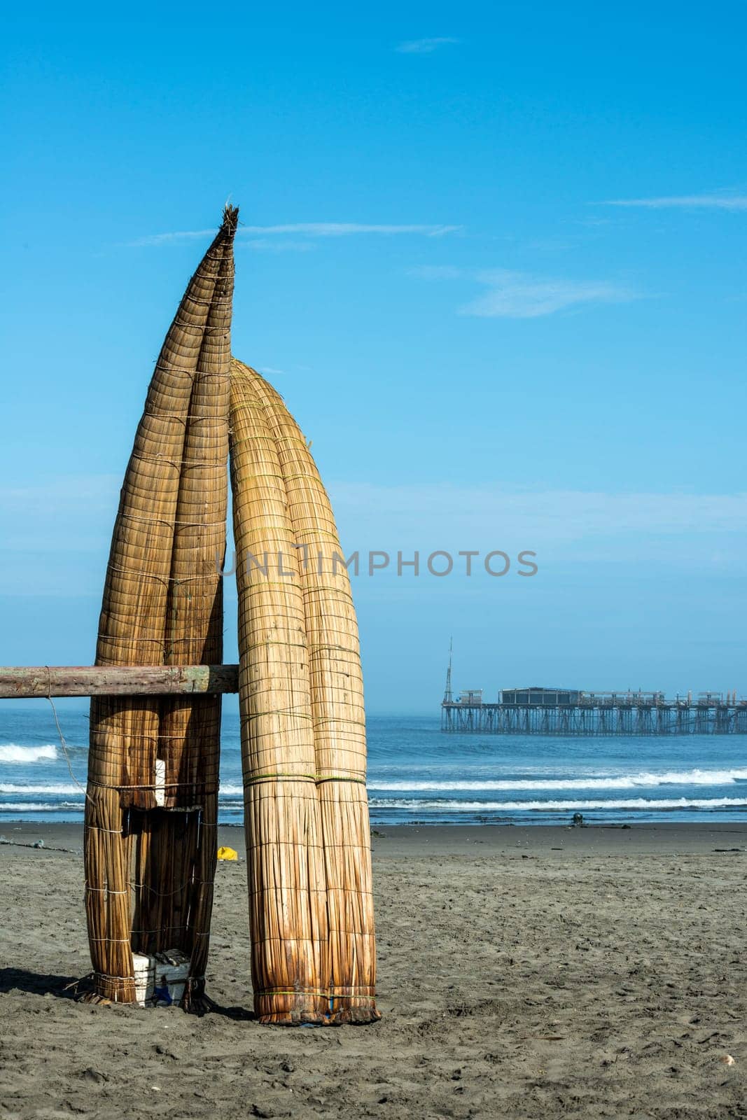 Traditional Peruvian small Reed Boats (Caballitos de Totora), straw boats still used by local fishermens in Peru. On the background – Famous pier at Pimentel
