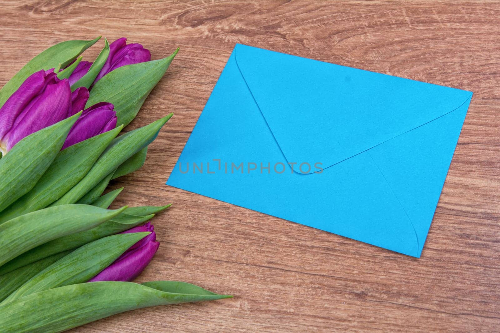 Blue envelope with purple tulips on a wooden background