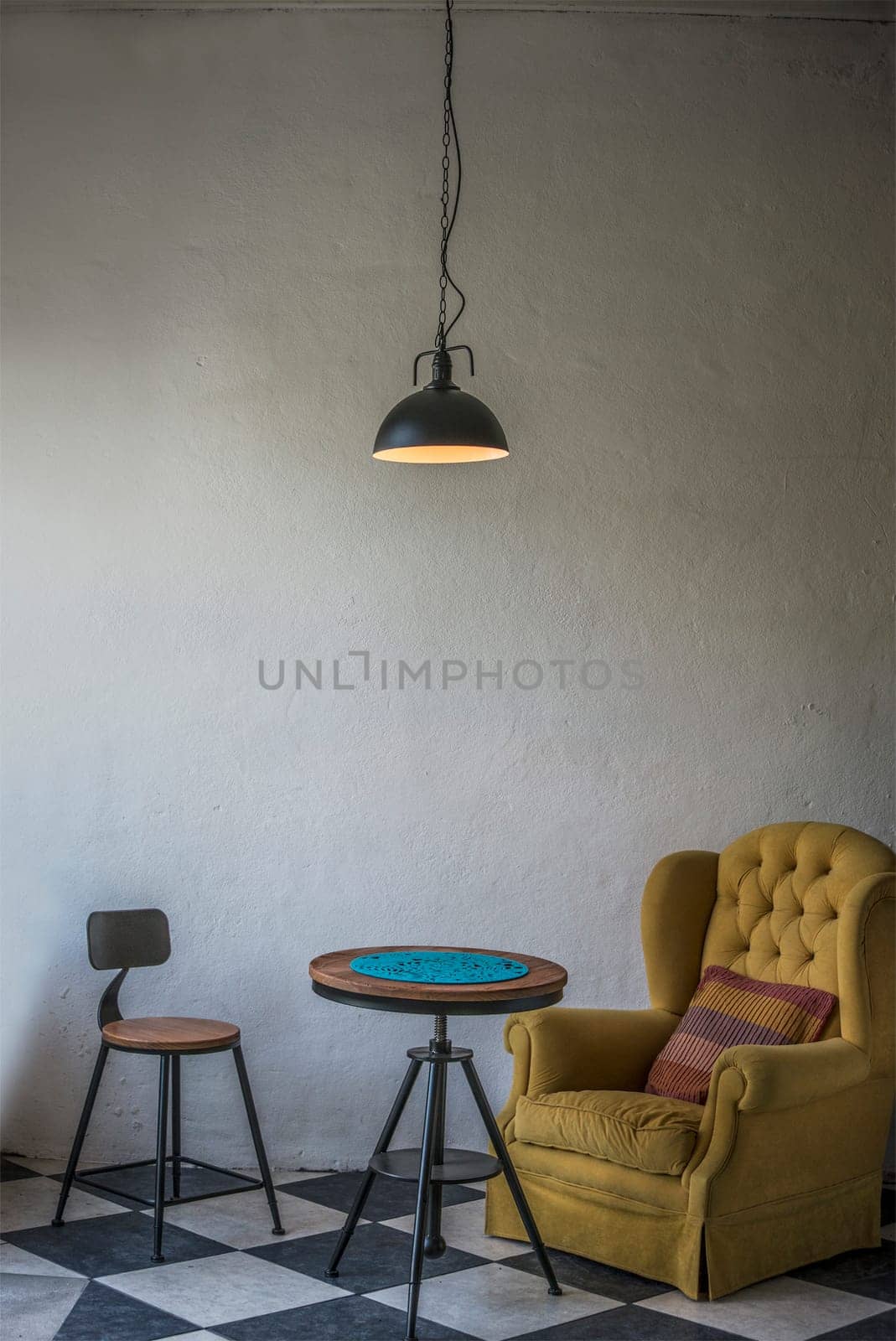 Vintage hipster loft interior with yellow armchair and an iron stool