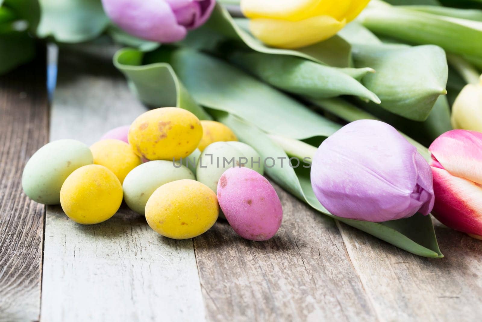 Close up of milk chocolate eggs on table with flowers.