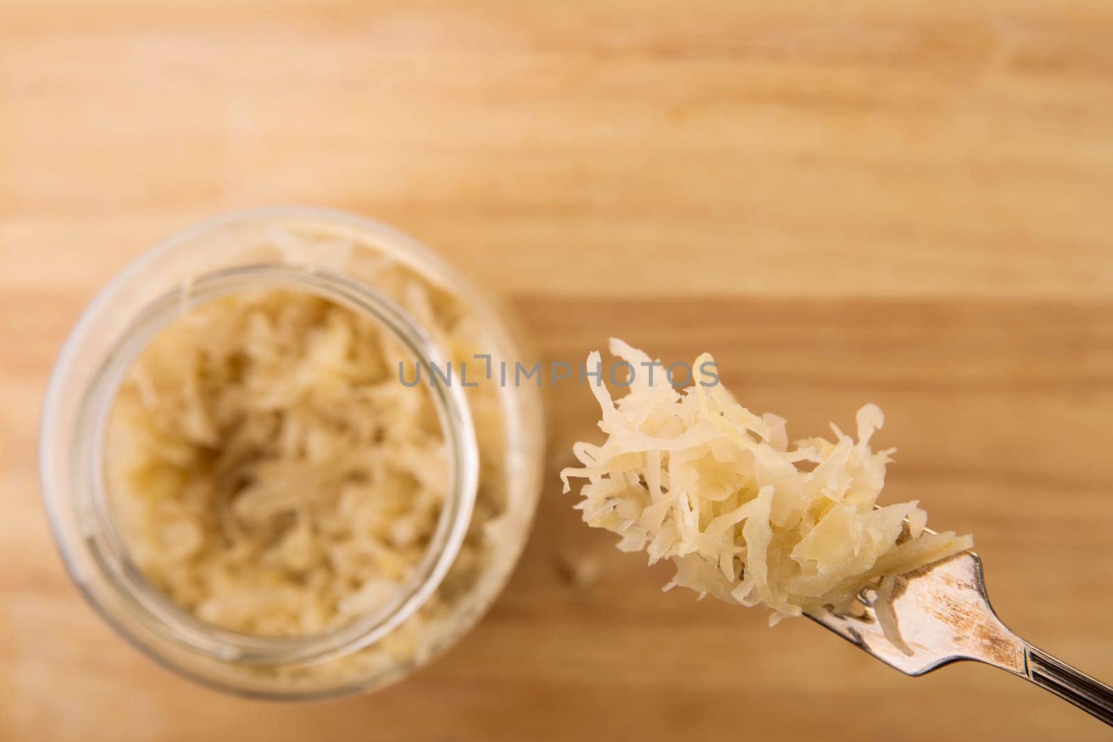 Sauerkraut on a fork with jar below and copy space.