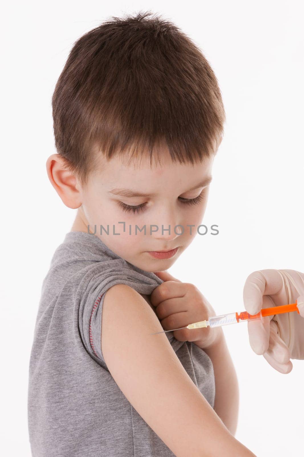 Doctor giving a child injection in arm on isolated image.