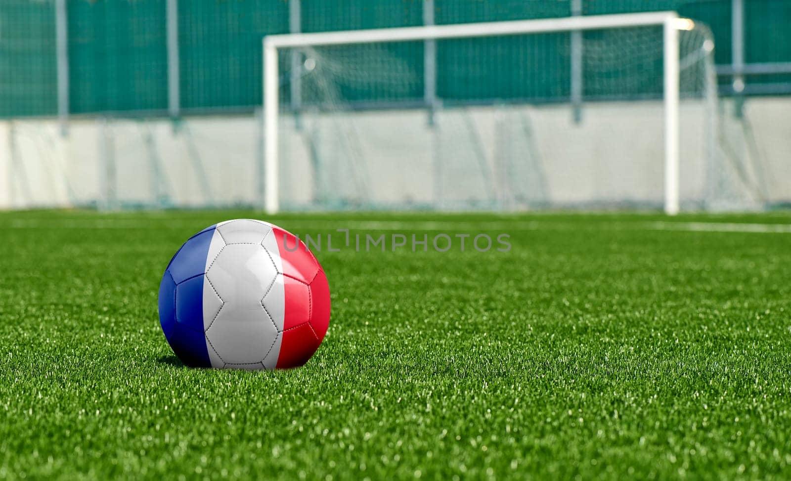 Soccer ball with the flag from France on the green field