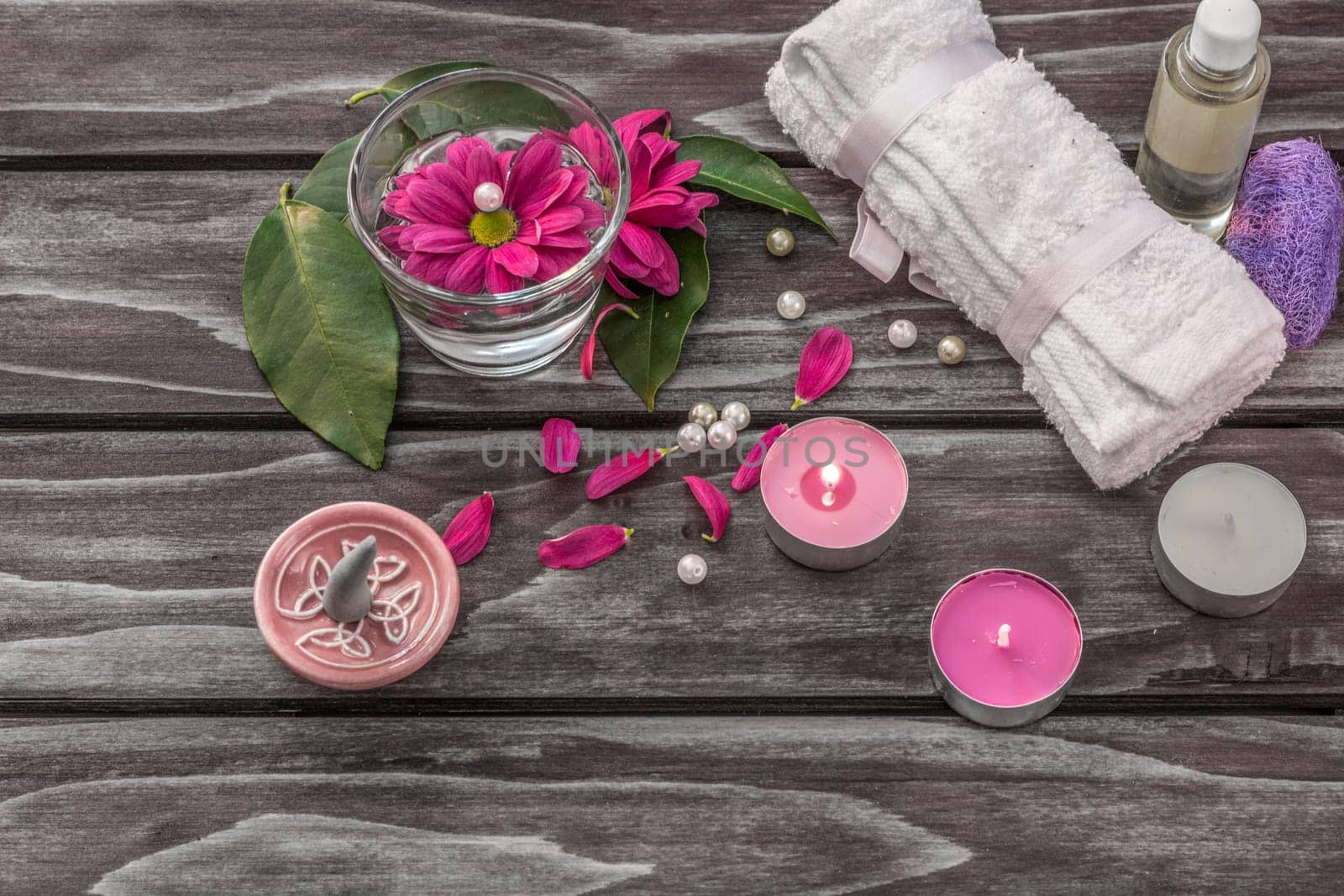 Spa concept. Lavender oil, flowers,cadles and bath white towels on wooden background.