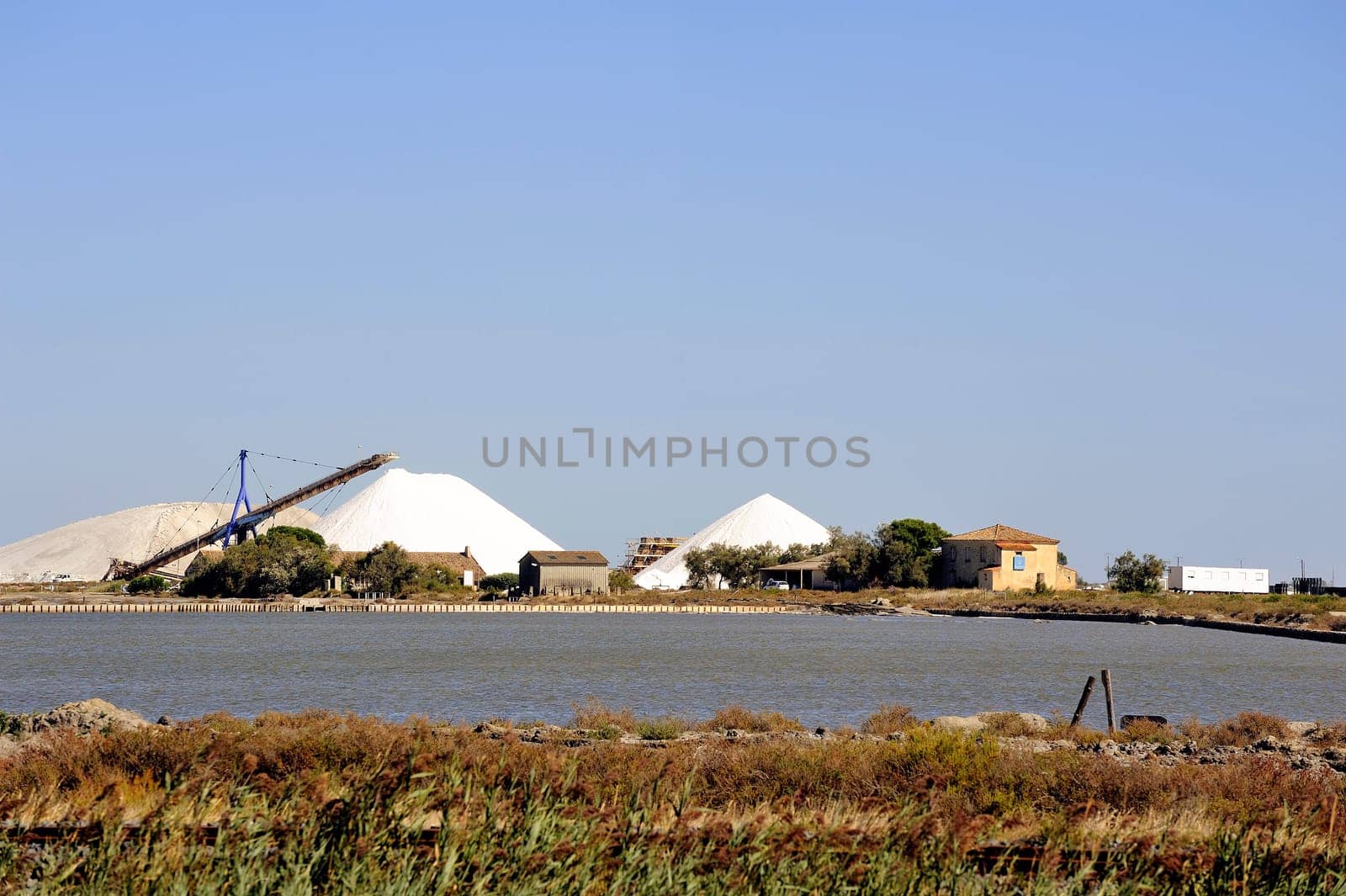 Site operating sea salt saline Aigues-Mortes with big machines and trucks working for the salt storage