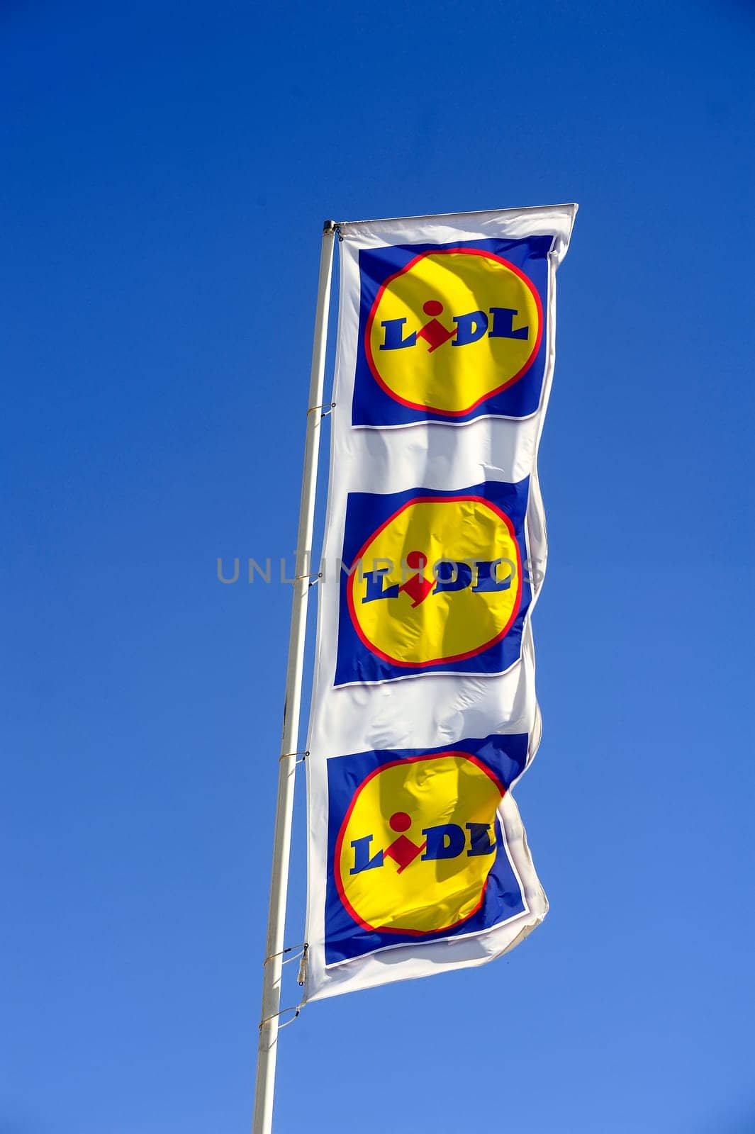 Flags in the colors of Lidl supermarket on the port of Grau-du-Roi windy day