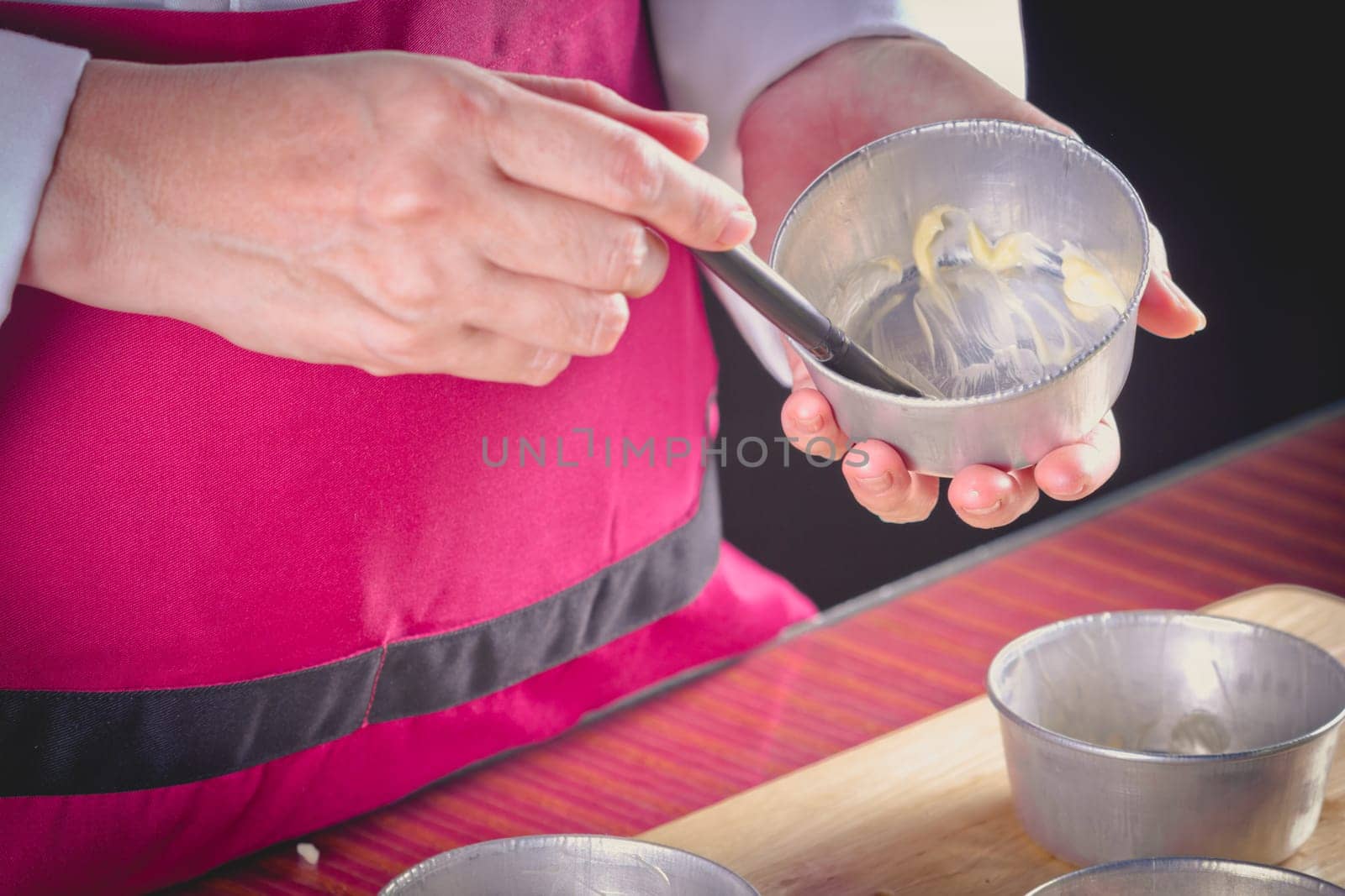Chef using pastry brush smearing butter in pastry molds