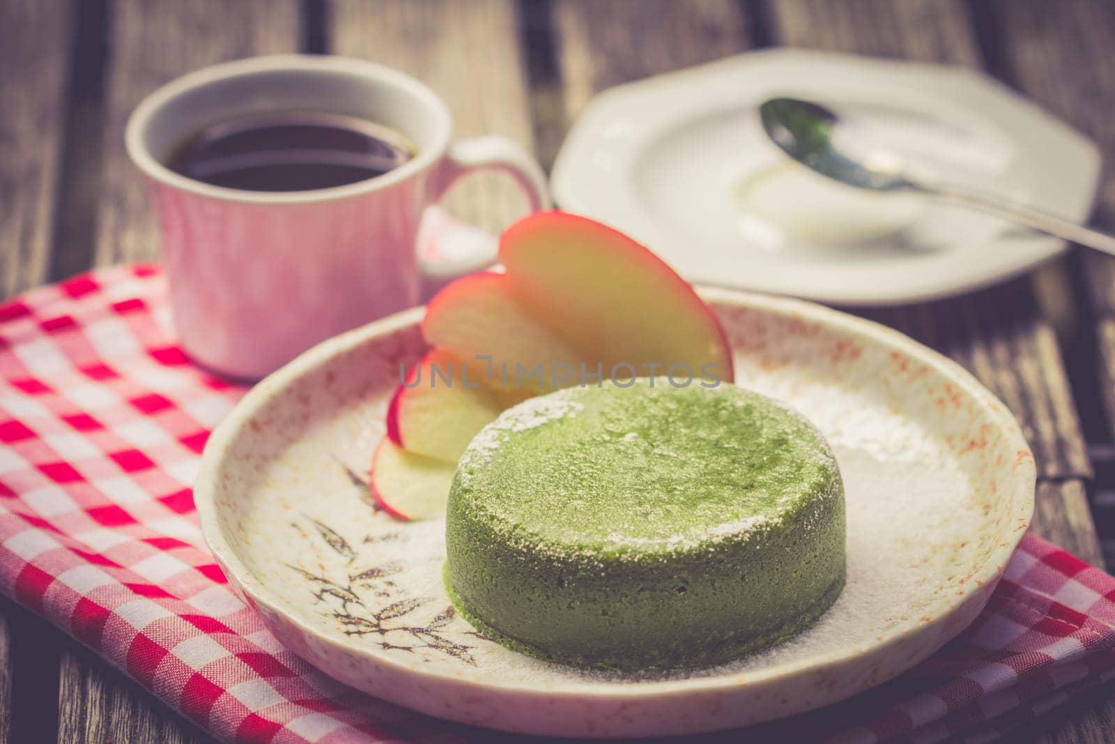 Green tea cake in palte with black coffee on wooden