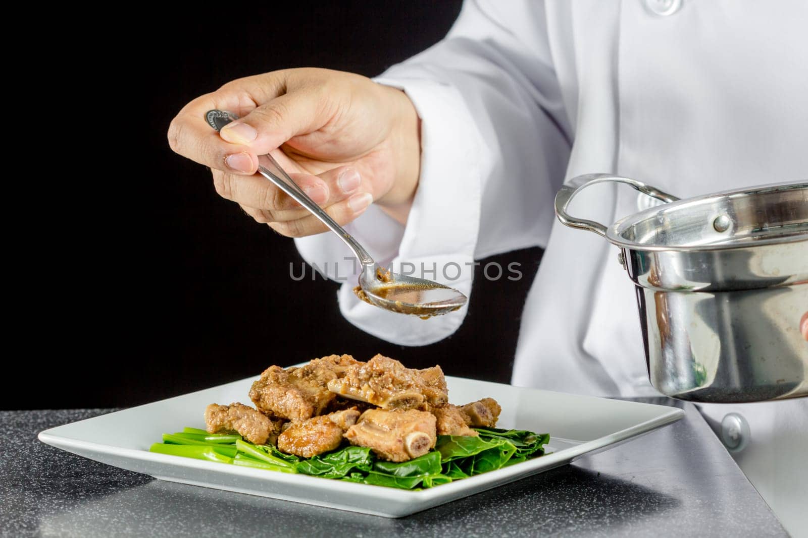 Chef making stir fried chinese kale and pork ribs in the kitchen