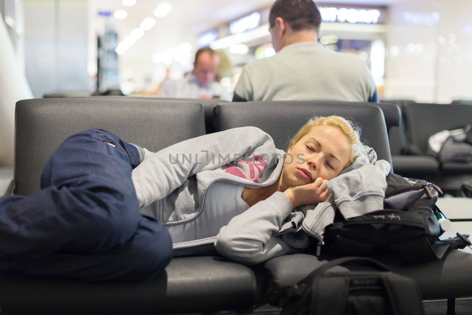 Tired female traveler sleeping on the airpot departure gates bench with all her luggage by her side.  Tireing travel concept.