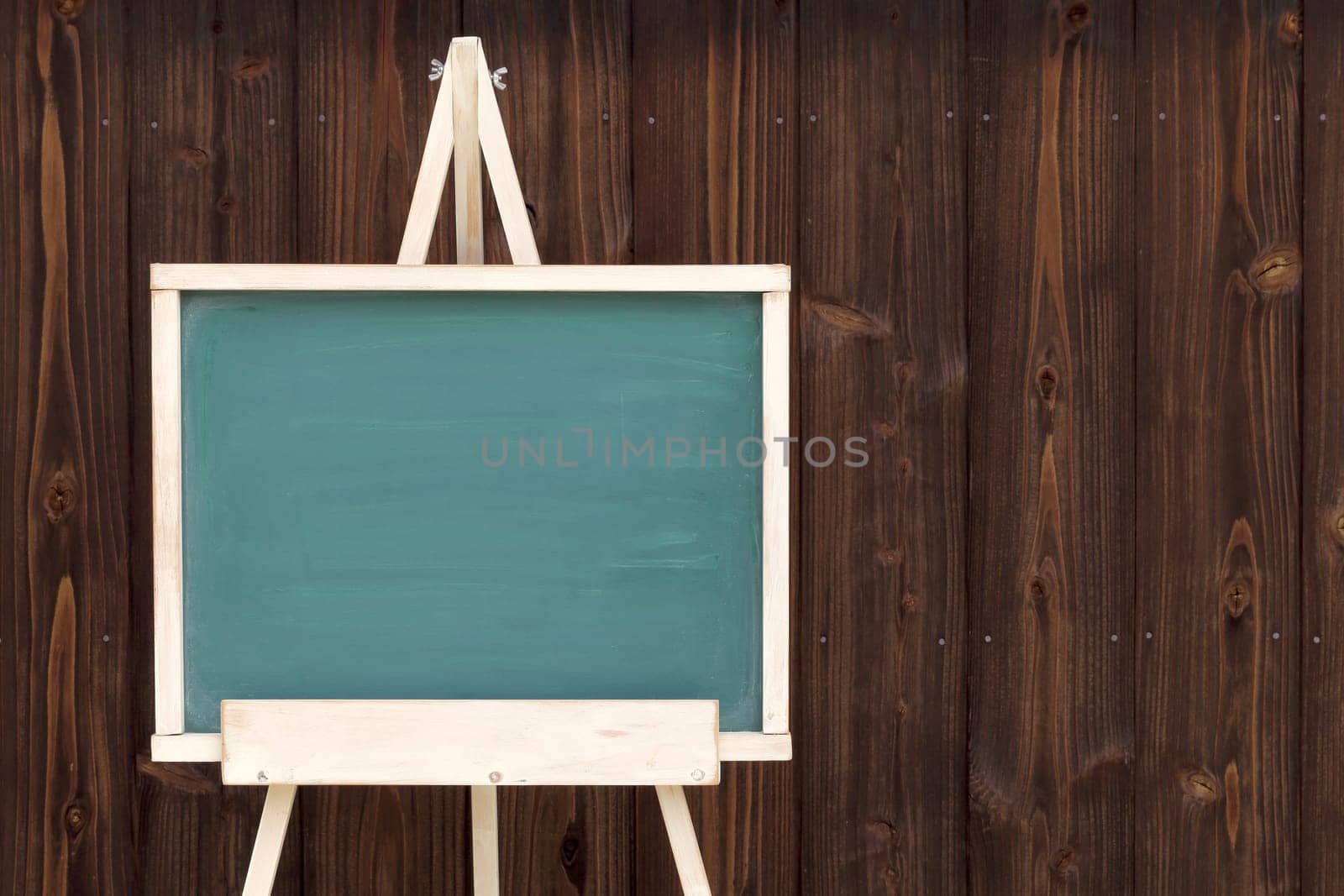 easel with blank chalkboard on a wood wall background