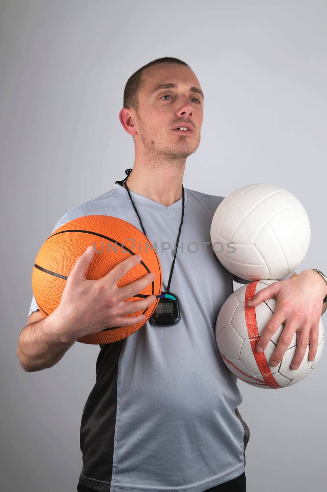 Coach is watching after his boys, holding a lot of balls.