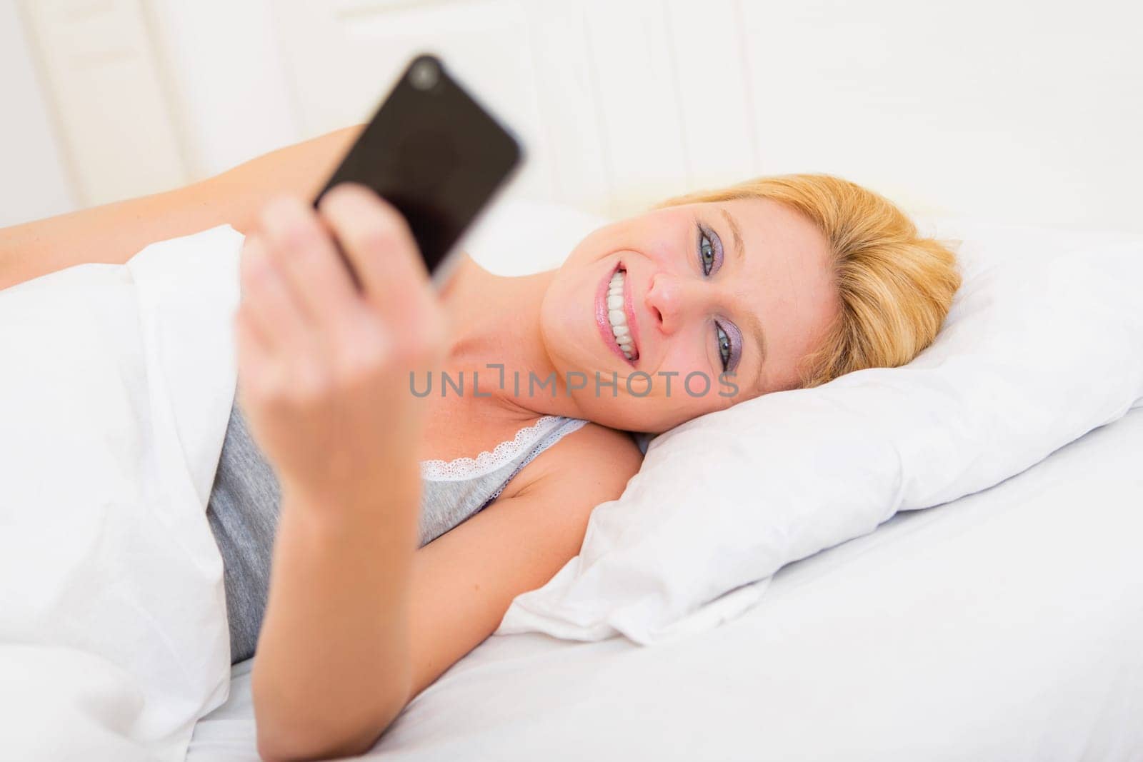 View of a Young attractive woman sending ttext in a bed