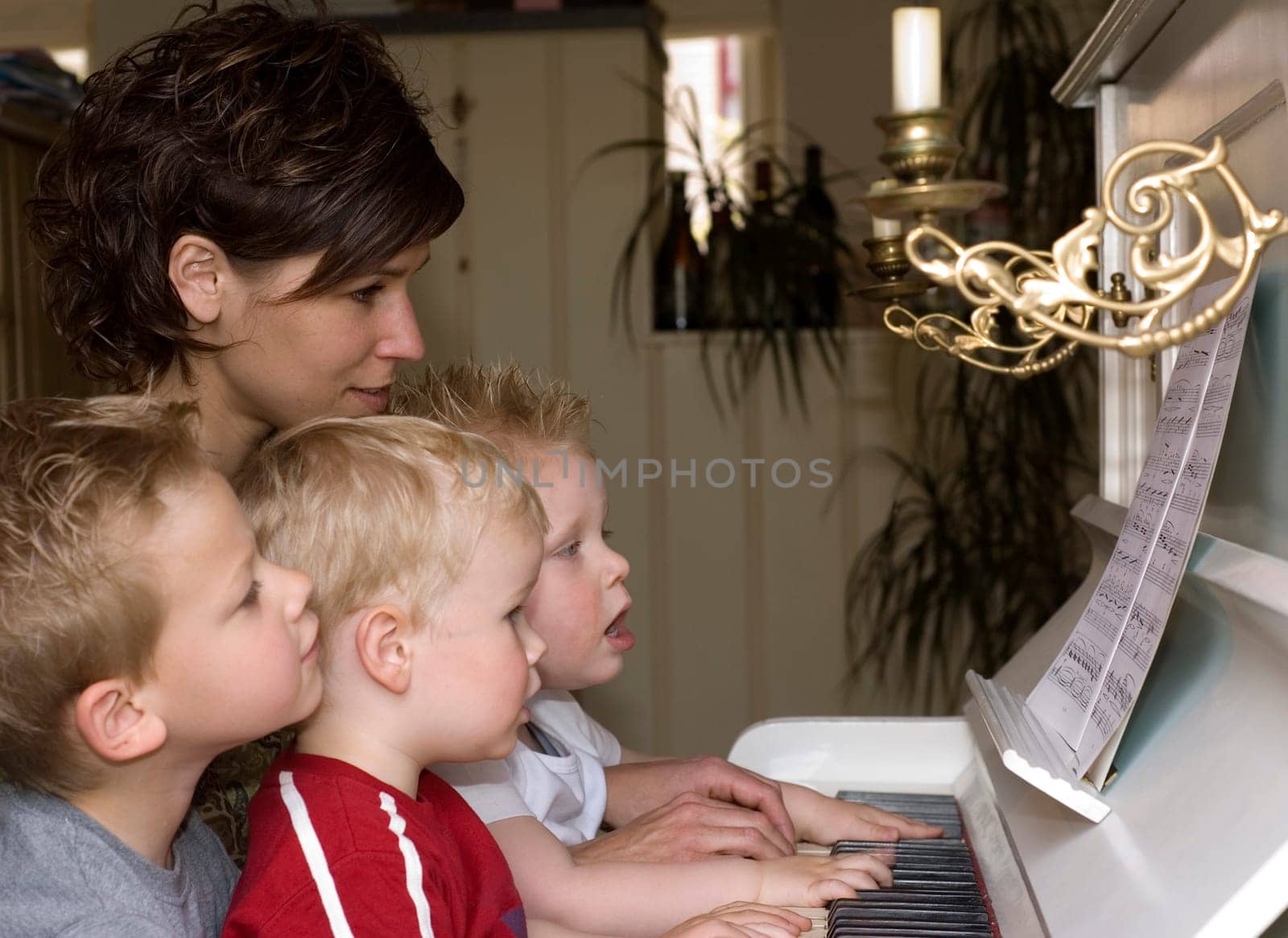 A cute family picture were four people are playing the piano