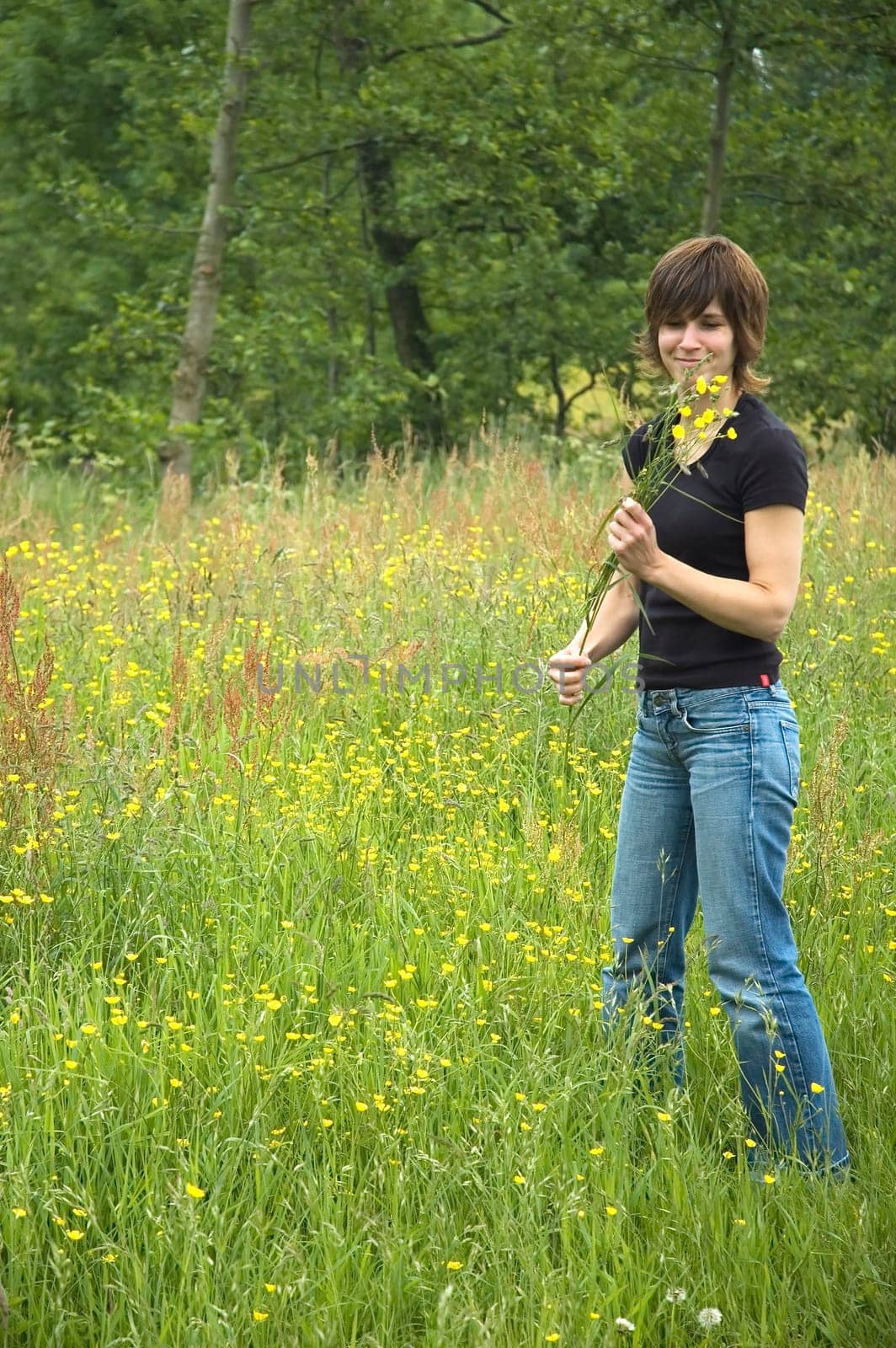 Beautiful girl picking flowers out of the grass fields for her boyfriend.