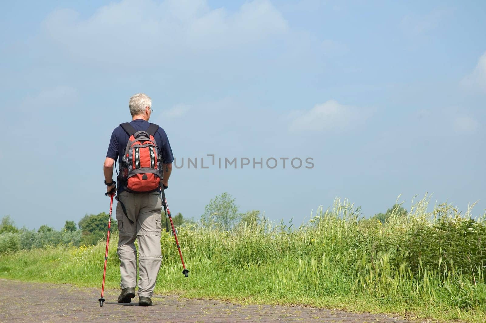 Senior man doing a Nordic Walk in the sun.