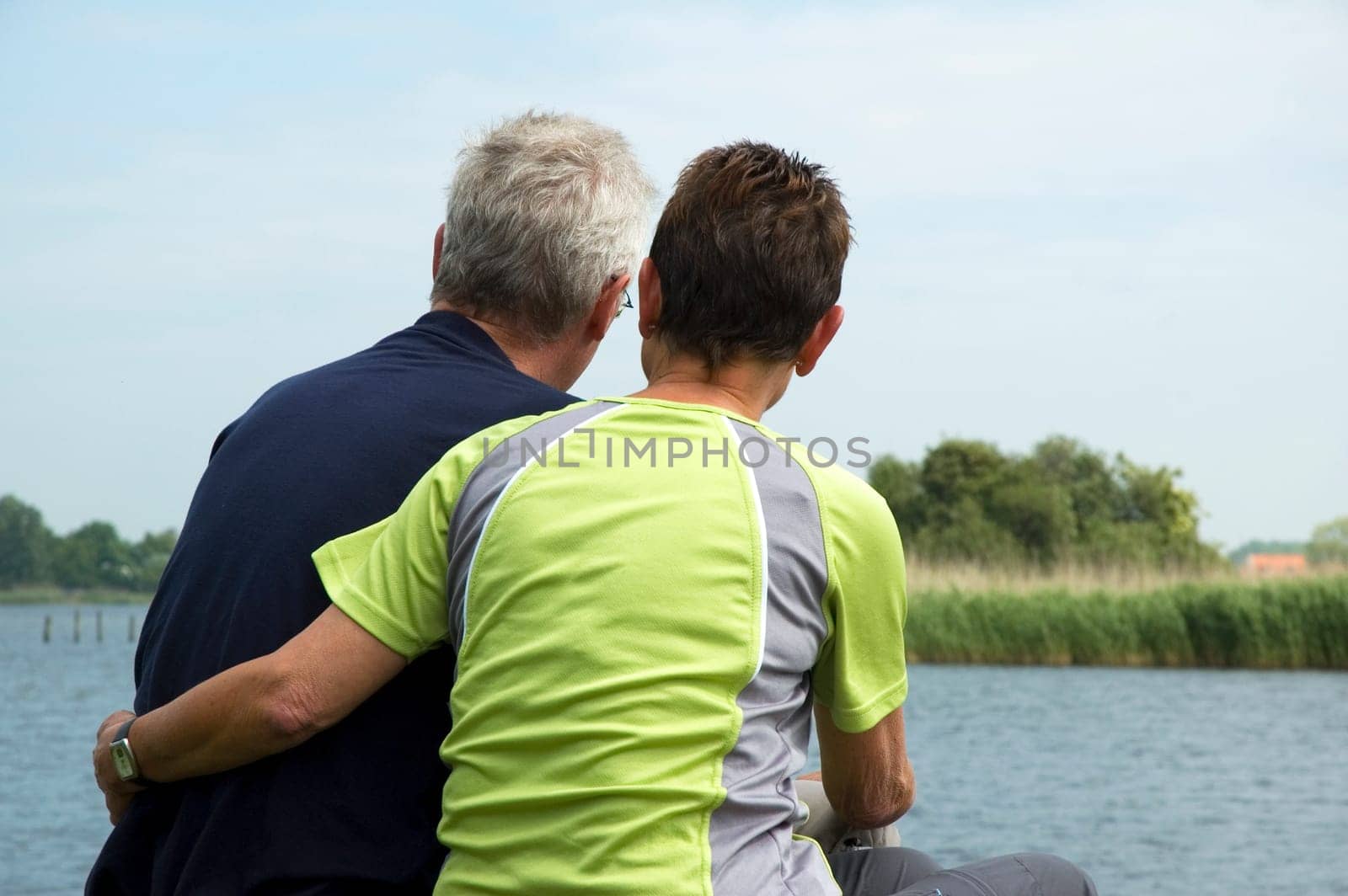 Senior couple sitting on a lonely place at a lake to think about their future and retirement.