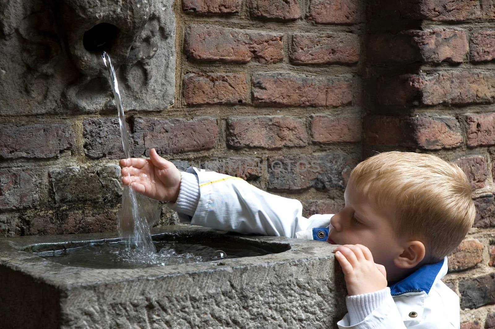 Boy holding his hand under a water stream to get fresh hands.