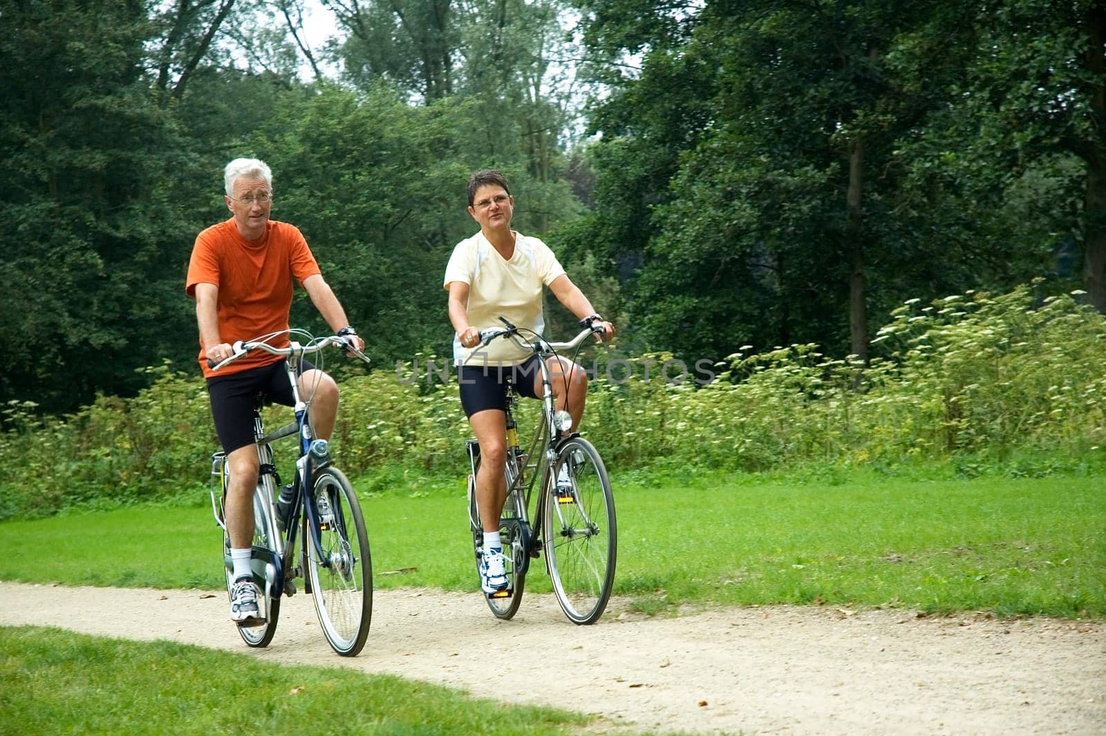 Active senior couple biking in the park.