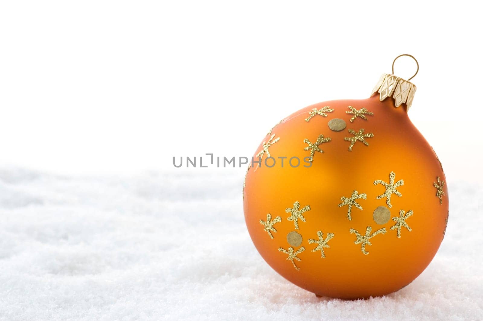 Golden Christmas ball on snow. Isolated on white.