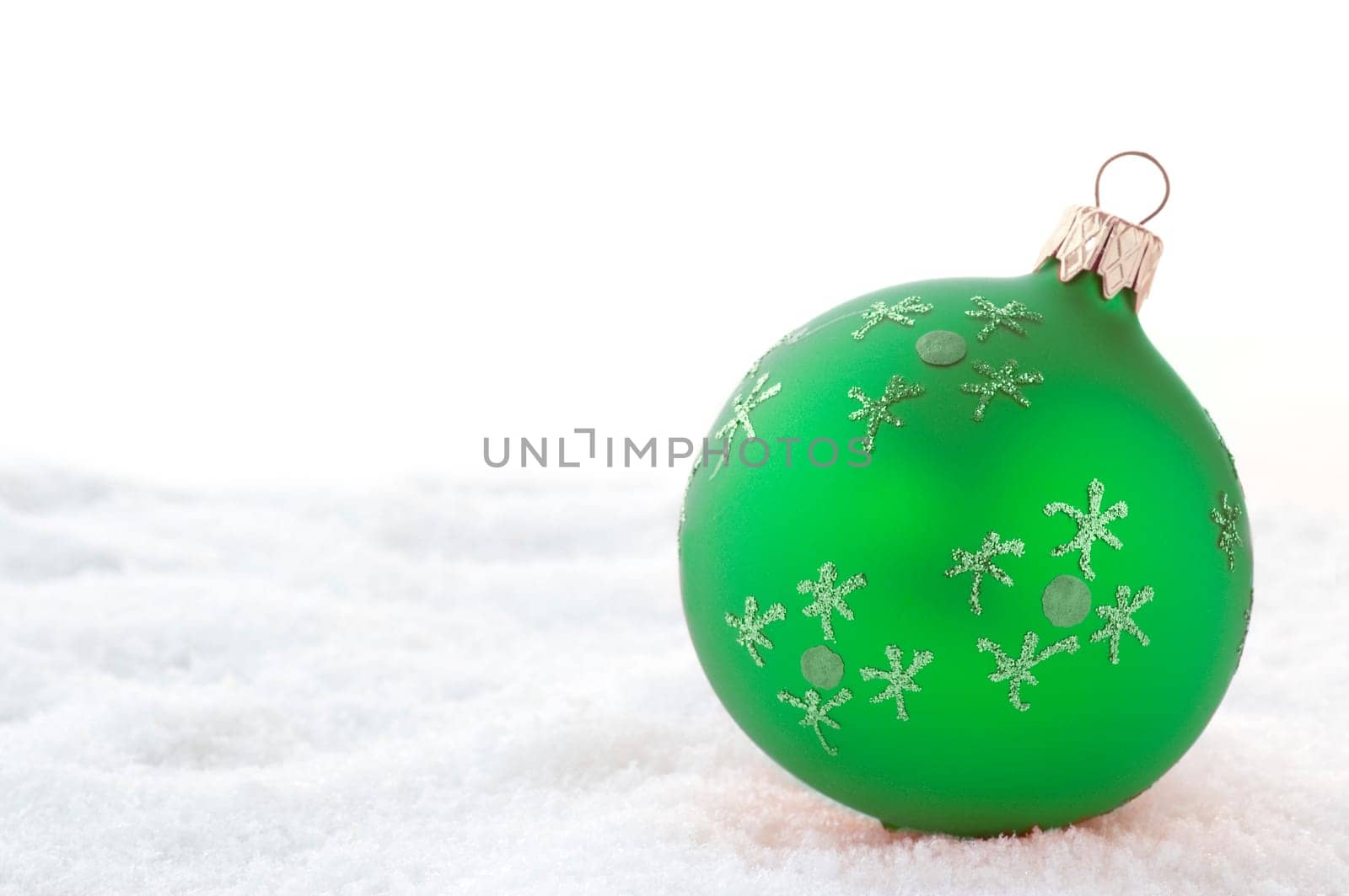 Green Christmas ball on snow. Isolated on white.