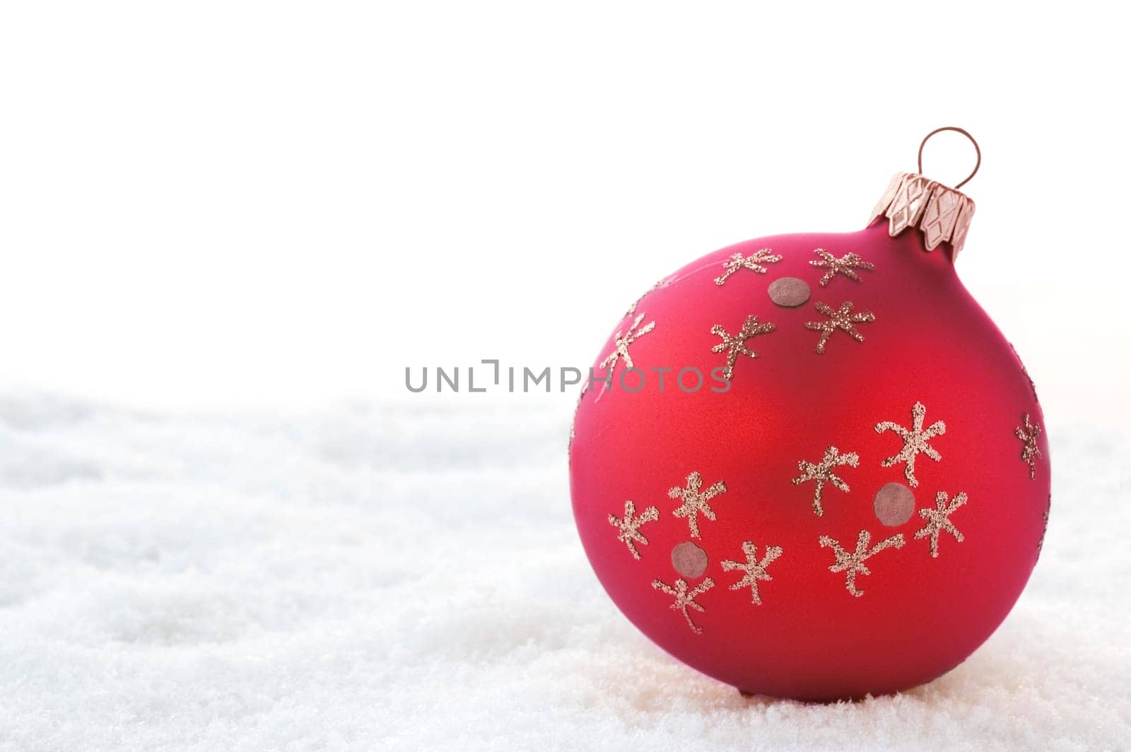 Red Christmas ball on snow. Isolated on white.