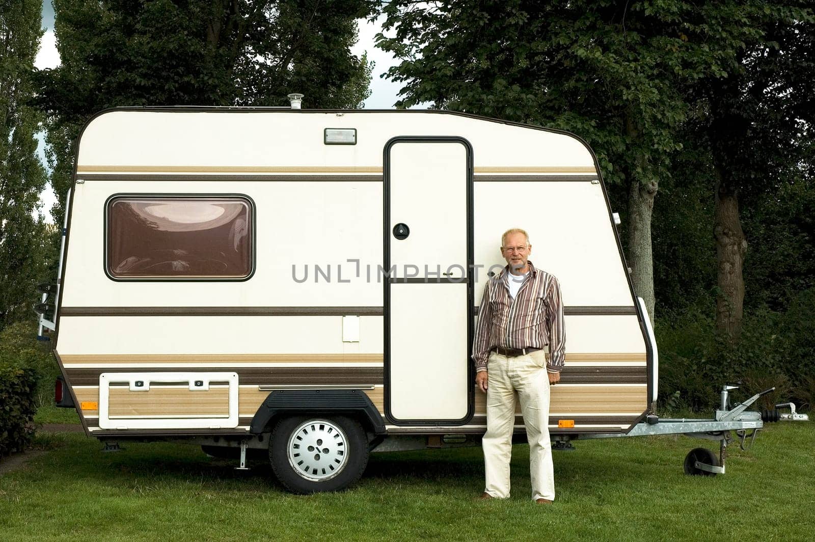 Senior man standing in front of his caravan