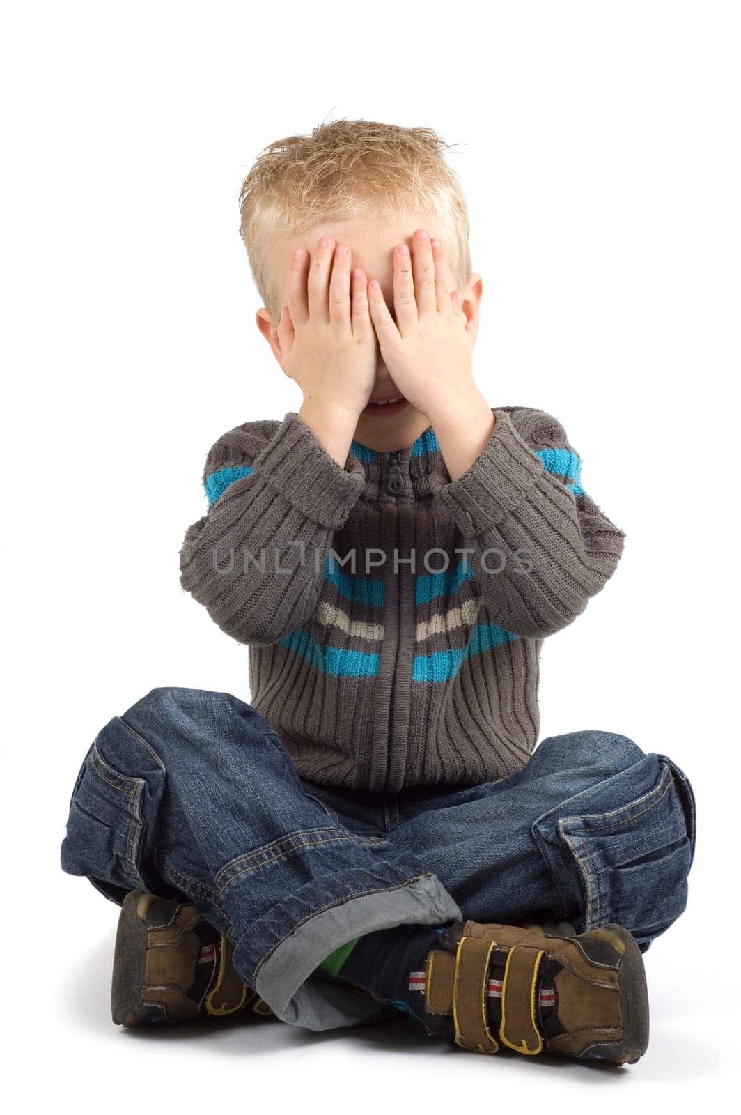 Boy holding his hands against his eyes.