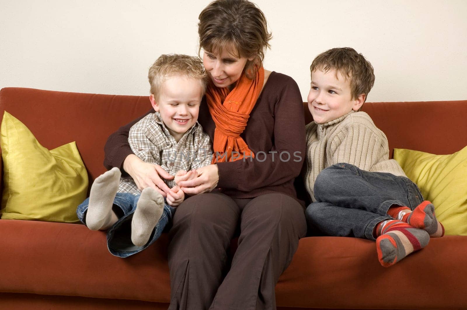 Nice family picture of a mother sitting with her two sons on a couch.