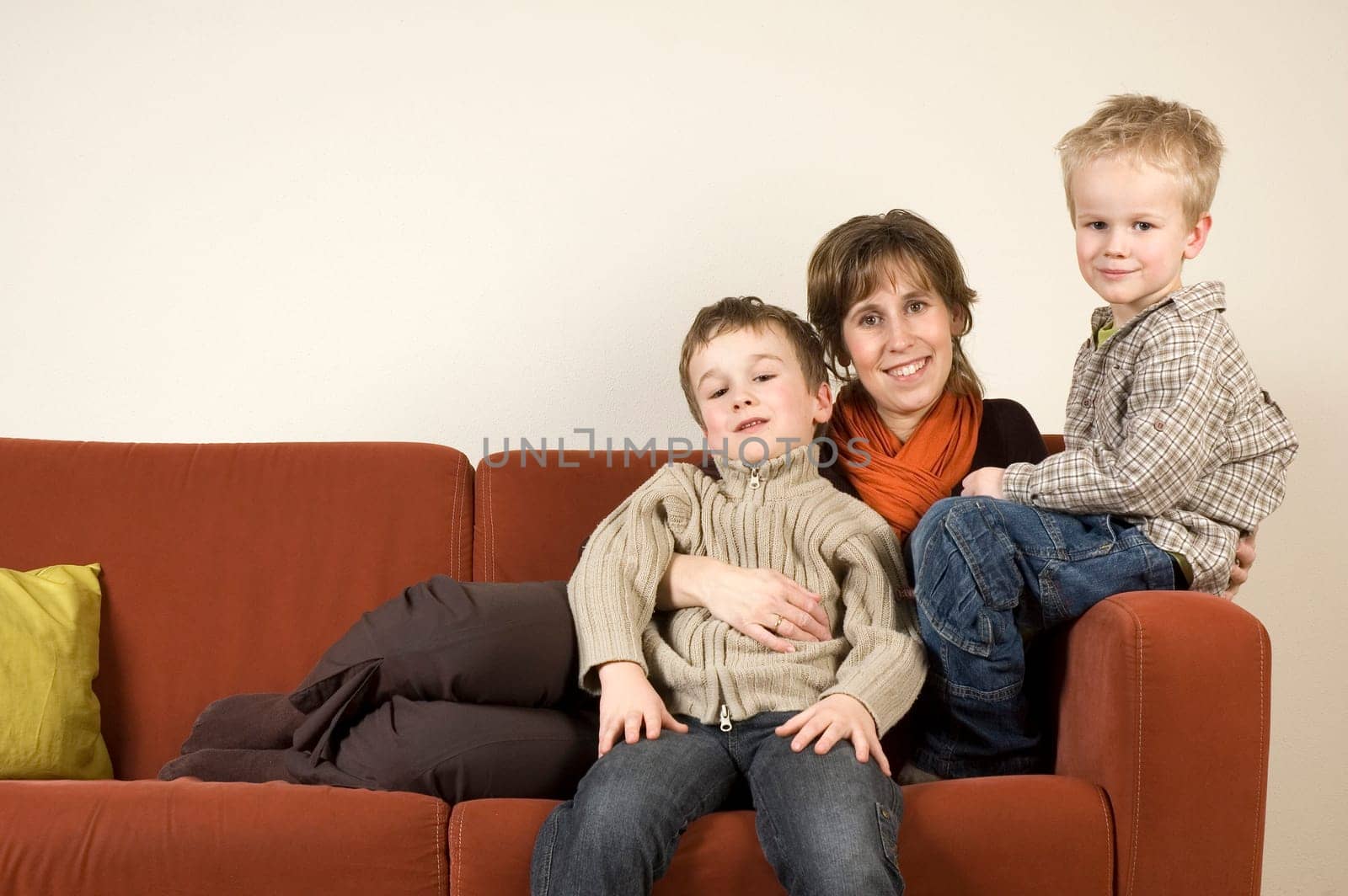 Nice family picture of a mother sitting with her two sons on a couch.