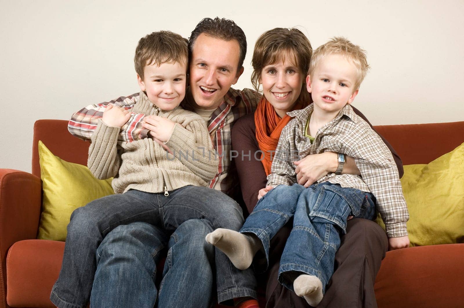 Nice family picture, sitting together on a couch.