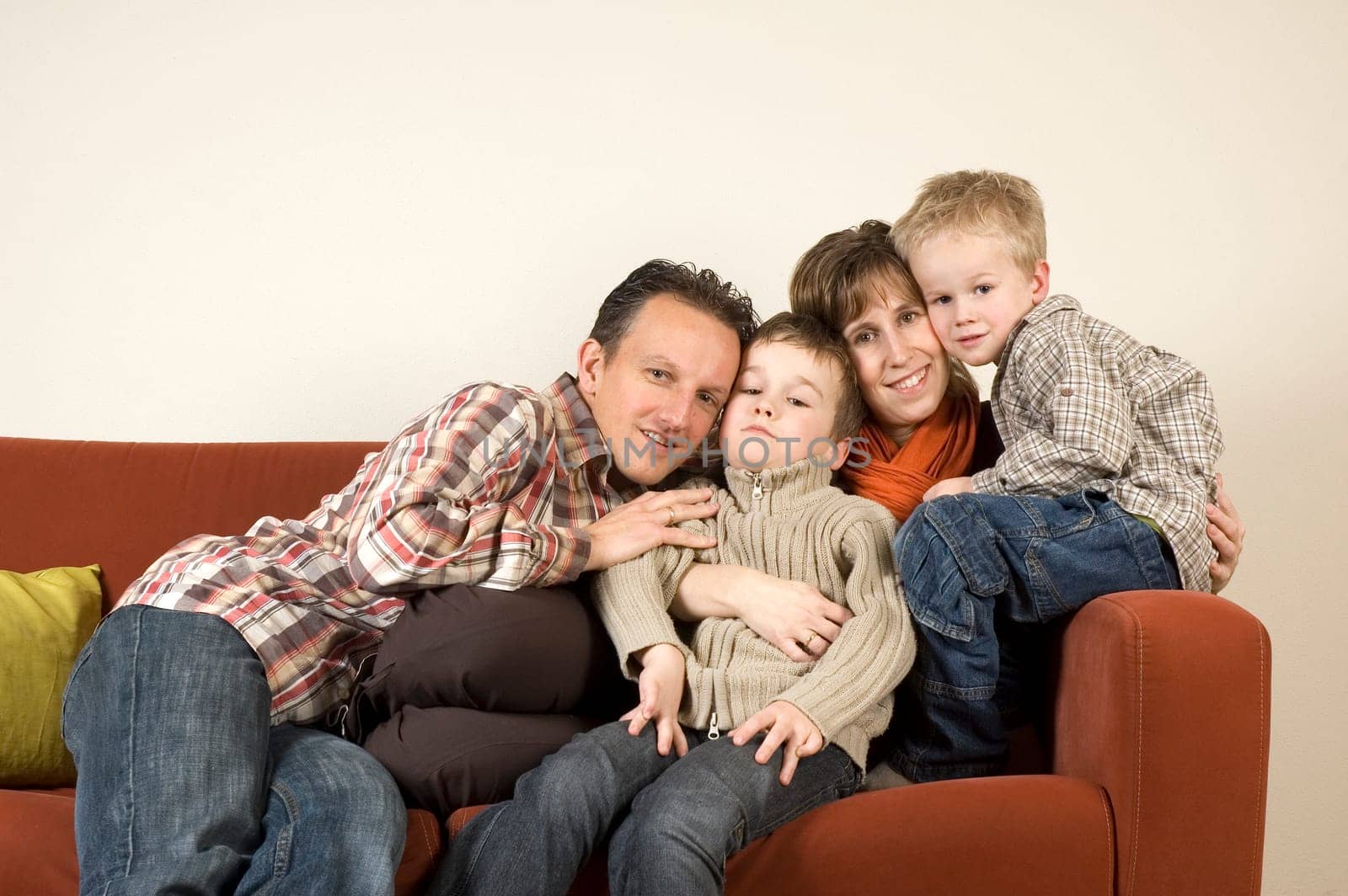 Nice family picture, sitting together on a couch.
