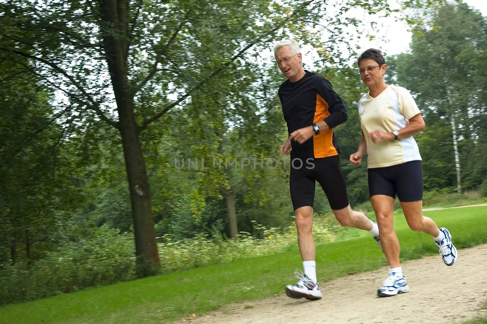 Active senior couple running in the woods.