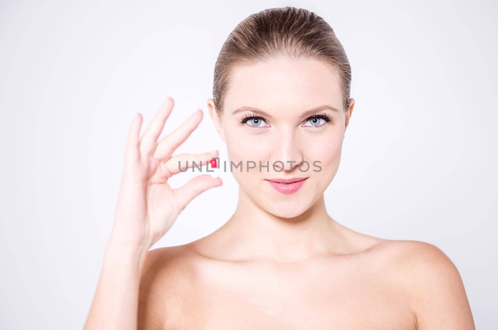 Naked woman holding a pill