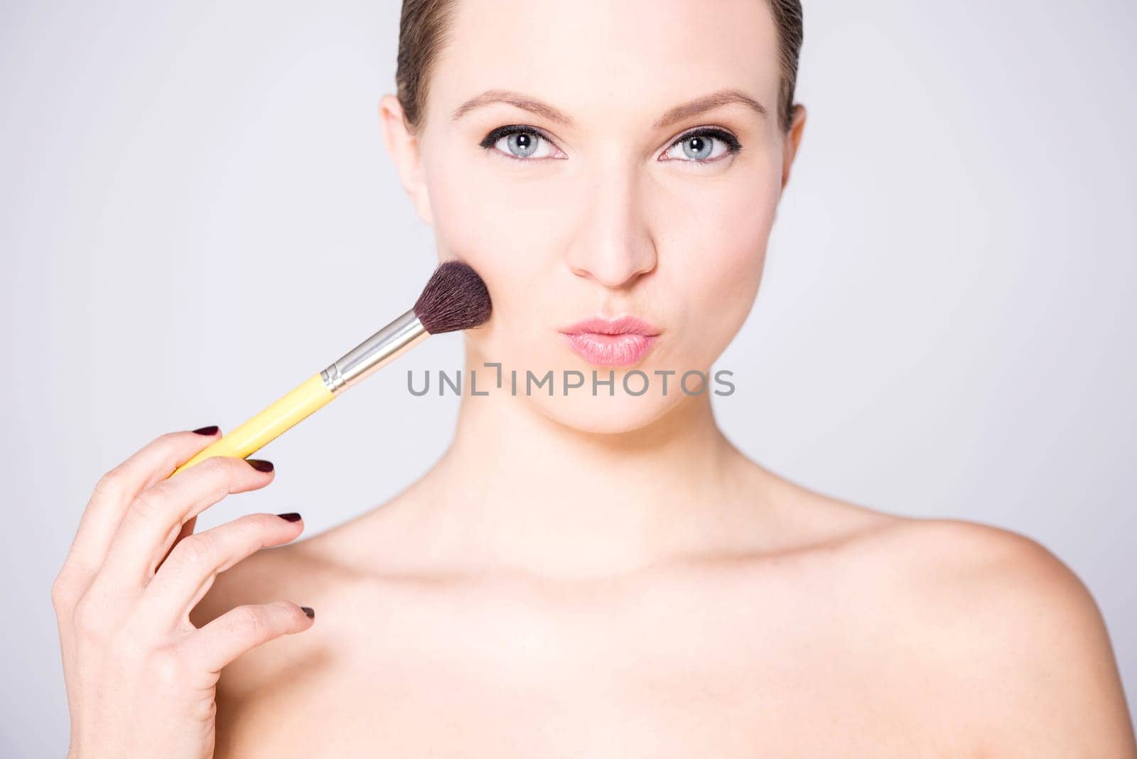 Bare shoulders attractive lady  applying blusher