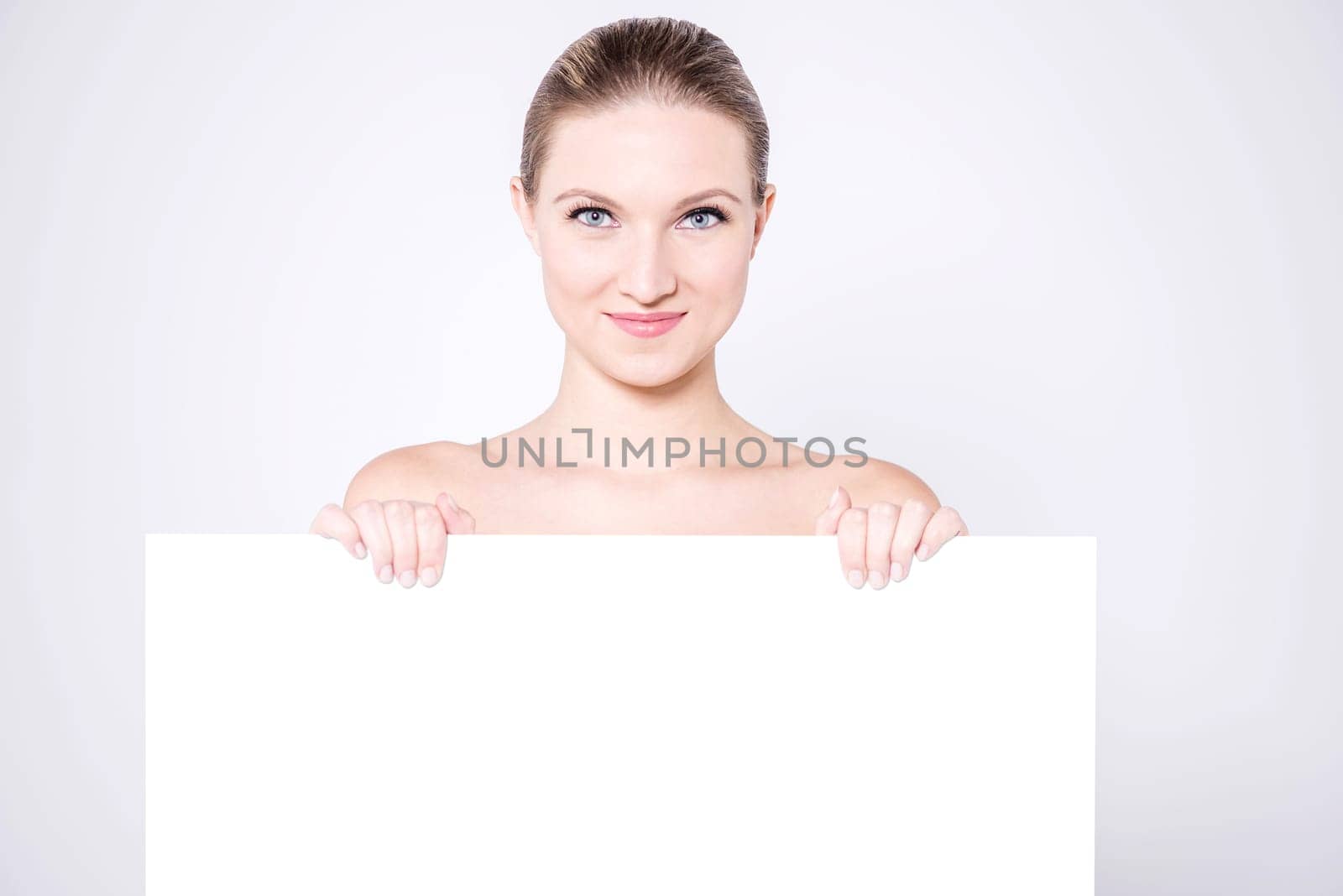 Nude woman hiding behind blank  whiteboard
