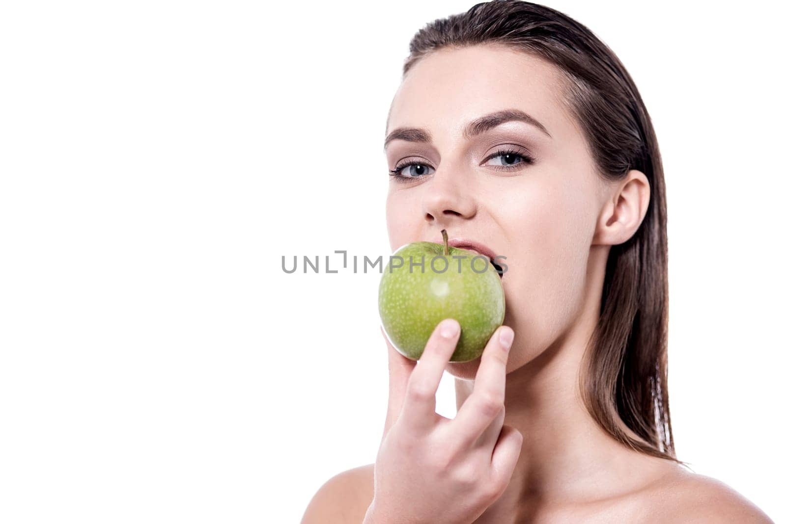 Young woman eating a green apple over white