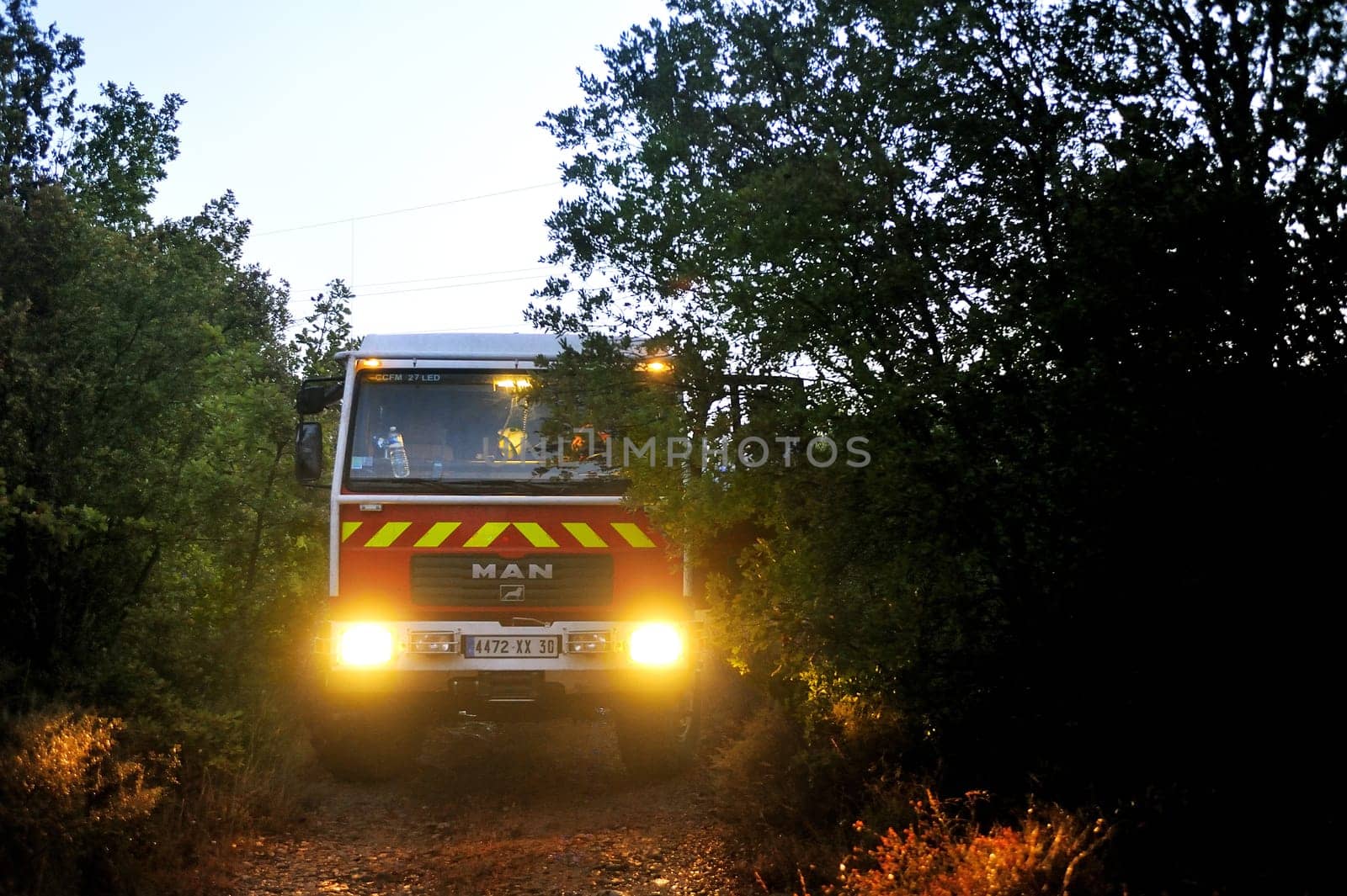 Fire trucks in a forest road the night after a forest fire in the French department of Gard.