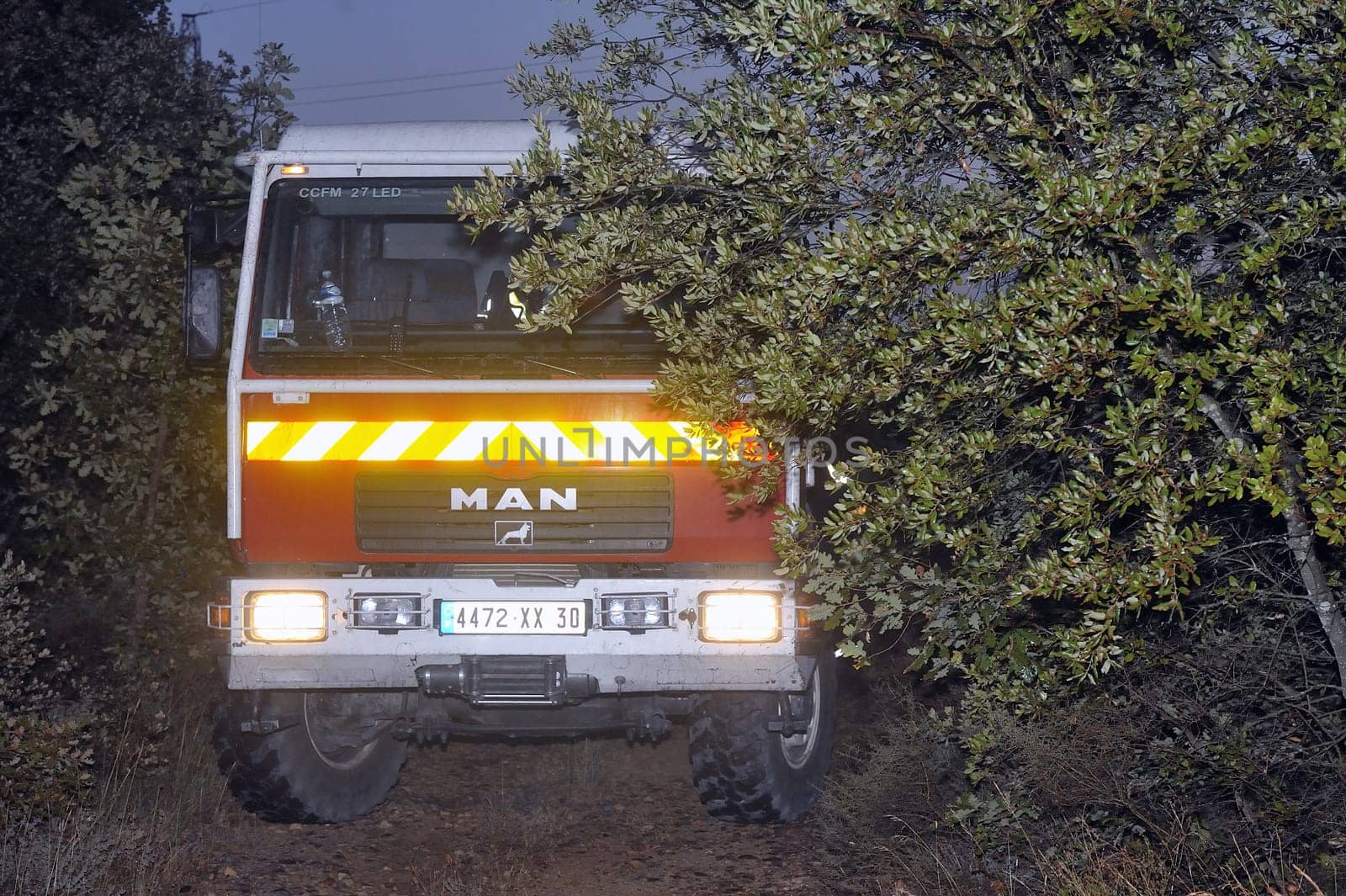 Fire trucks in a forest road the night after a forest fire in the French department of Gard.