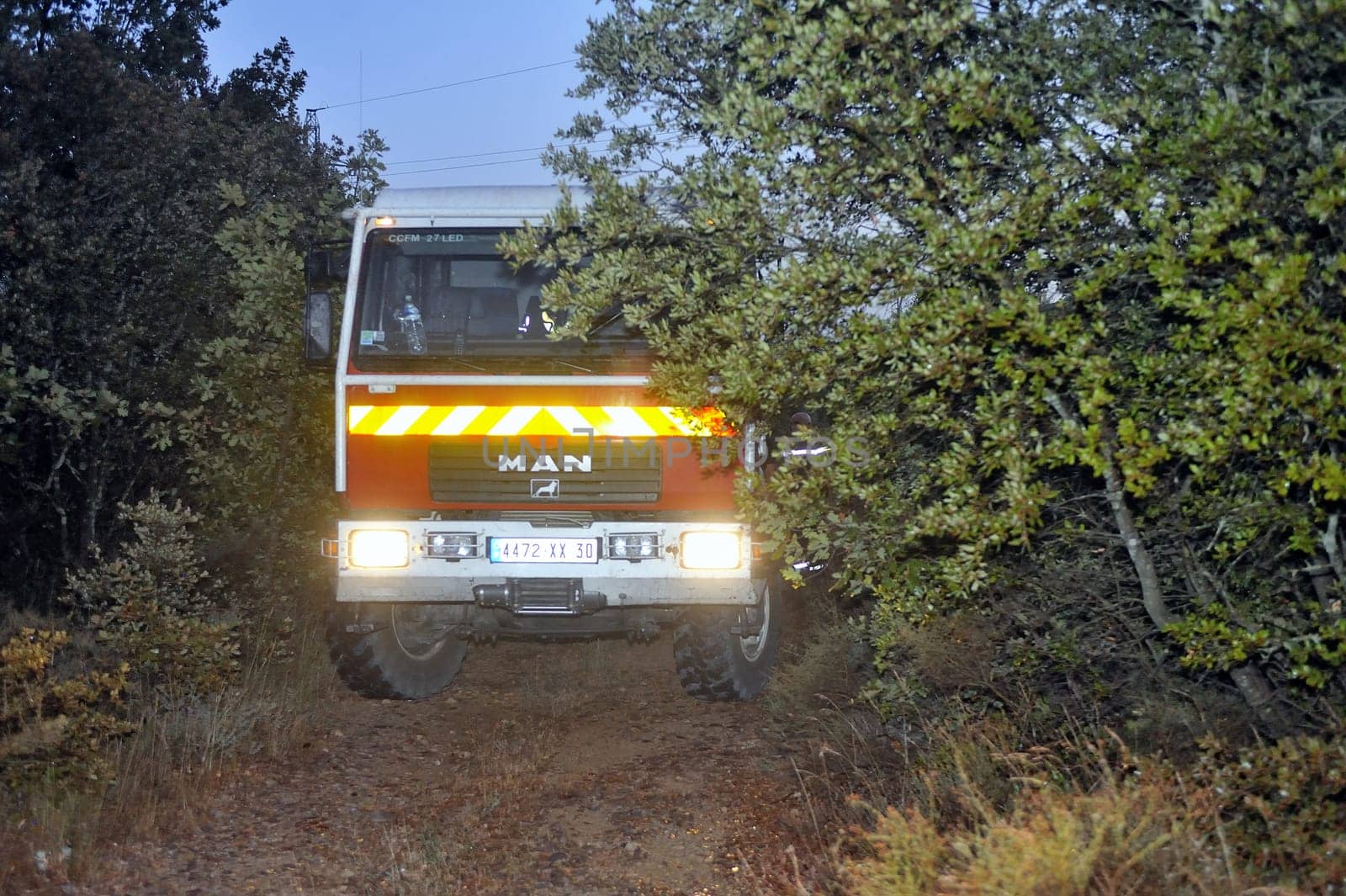 Fire trucks in a forest road the night after a forest fire in the French department of Gard.