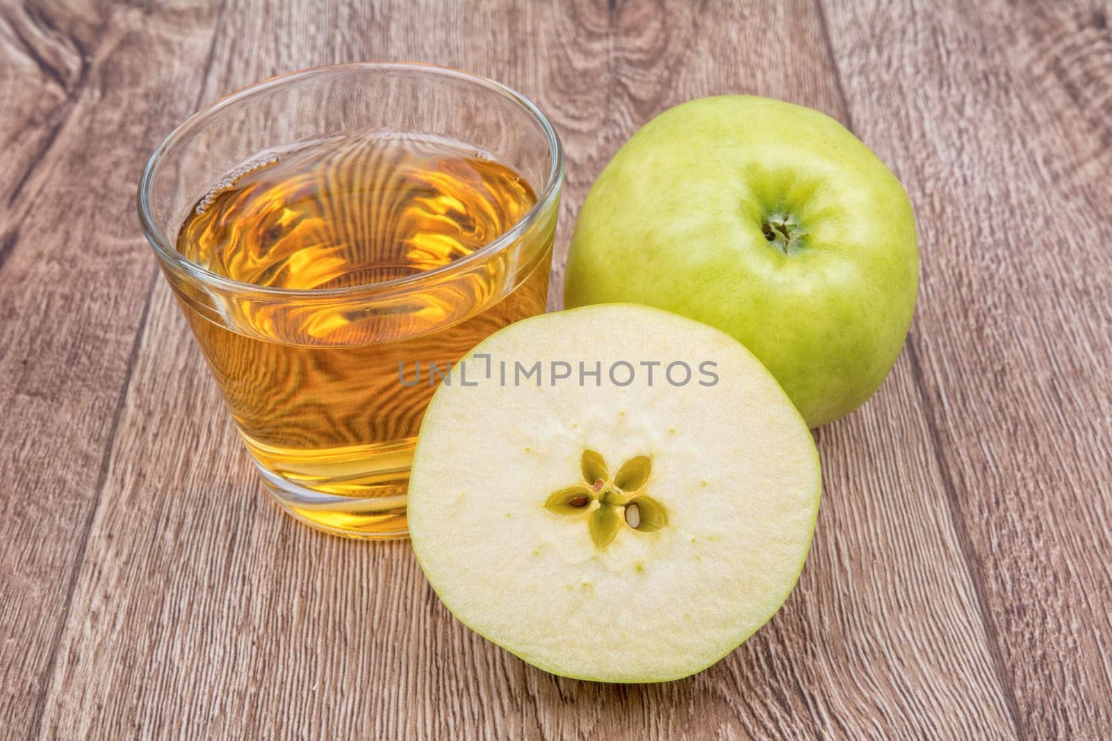 Green apples and juice on a wooden background