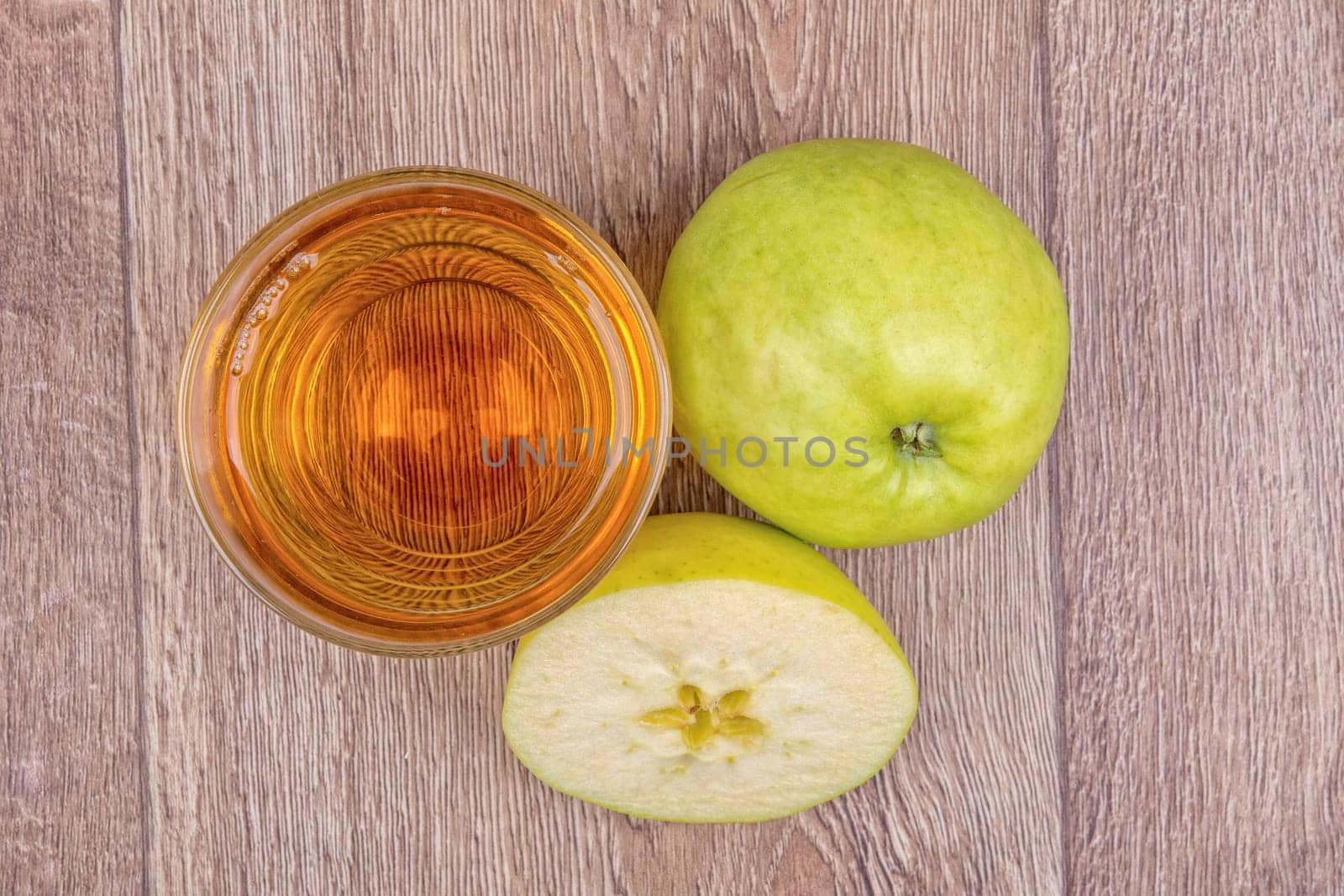 Green apples and juice on a wooden background